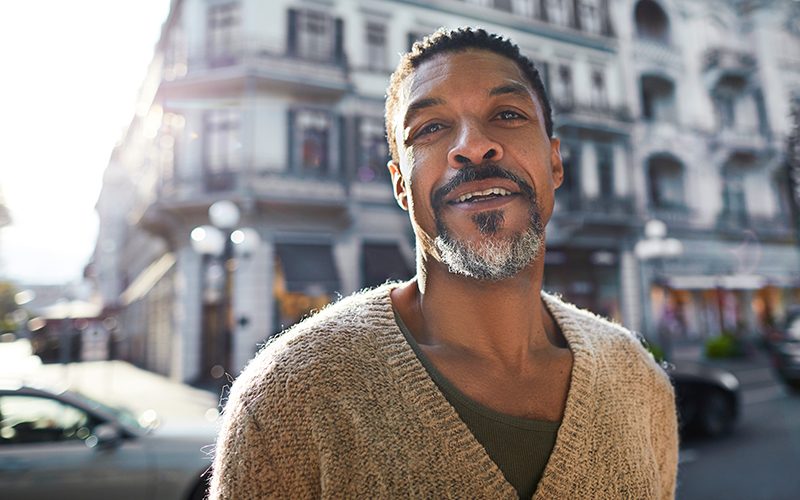 Man smiling in front of building